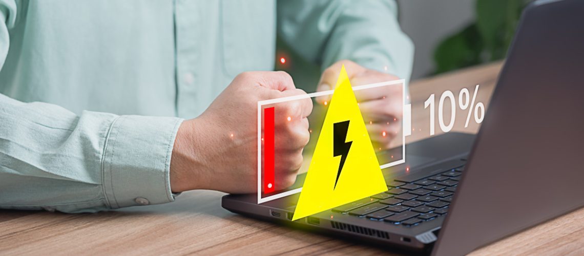 Young man is angry and frustrated when he learns that his the laptop computer's battery is dead and did not bring the charger adapter. No power battery.